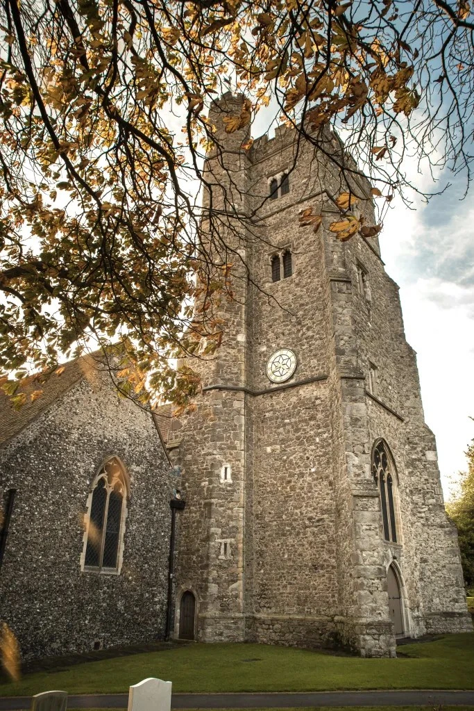 A ground-level view of St Margaret’s church tower framed by trees